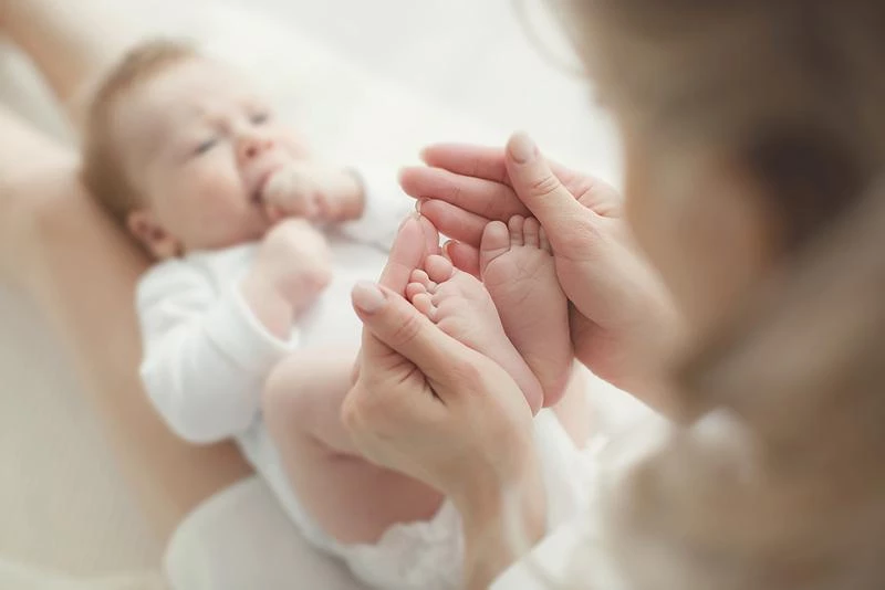 Picture of a baby lying down while parent plays with their feet. Picture of a baby lying down while parent plays with their feet.